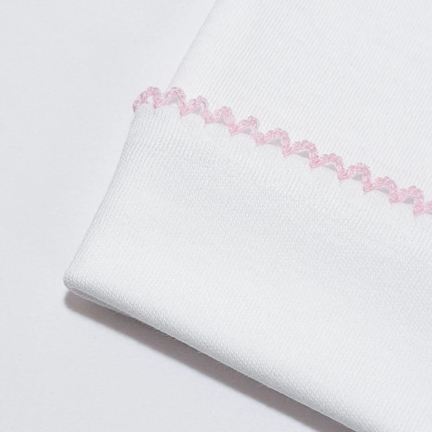 Detalle de gorro blanco con puntilla de color en el doblez rosa