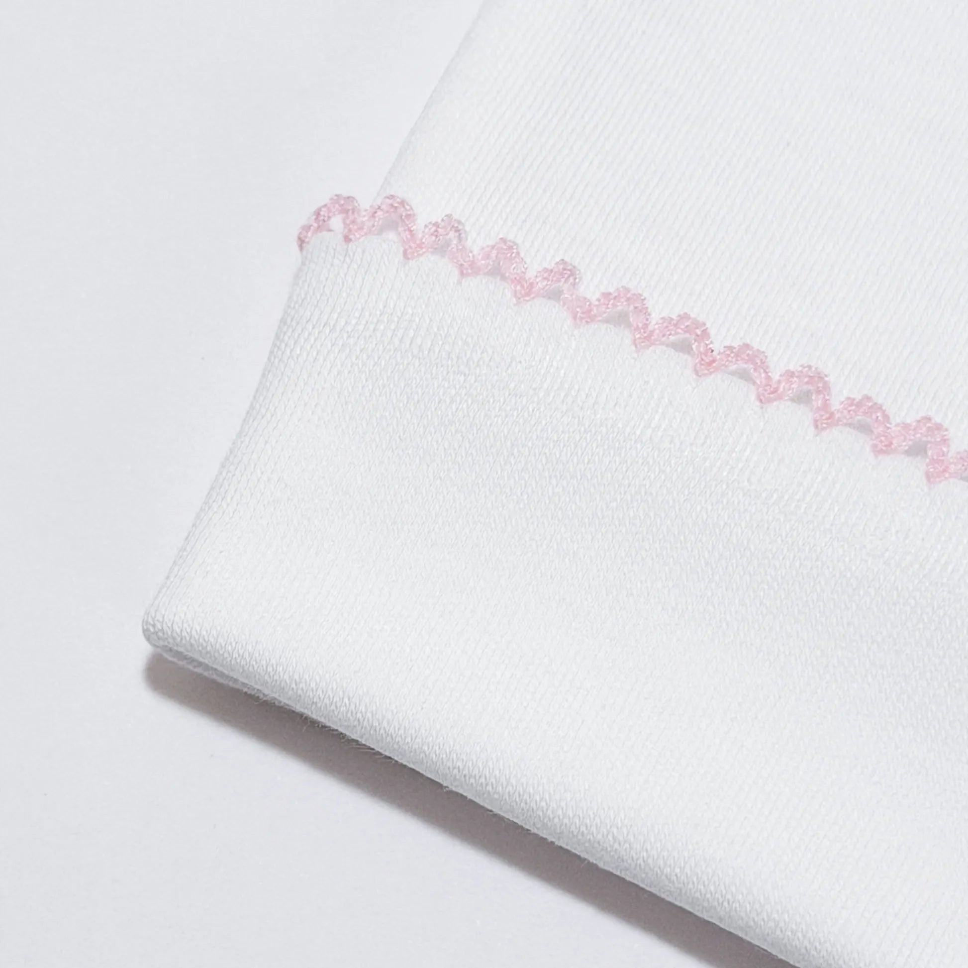 Detalle de gorro blanco con puntilla de color en el doblez rosa