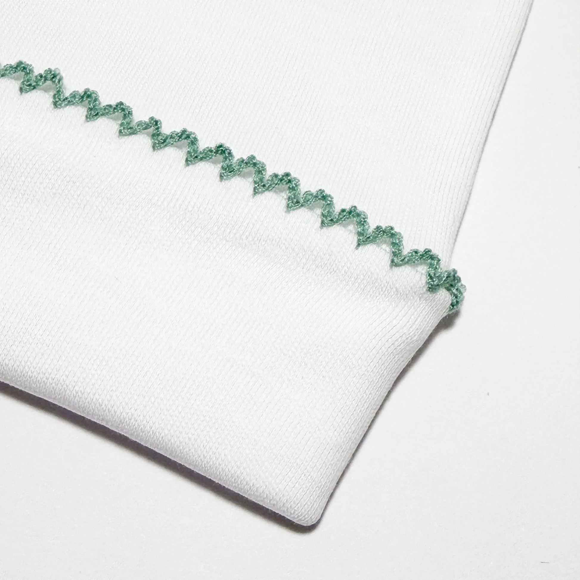 Detalle de gorro blanco con puntilla de color en el doblez verde
