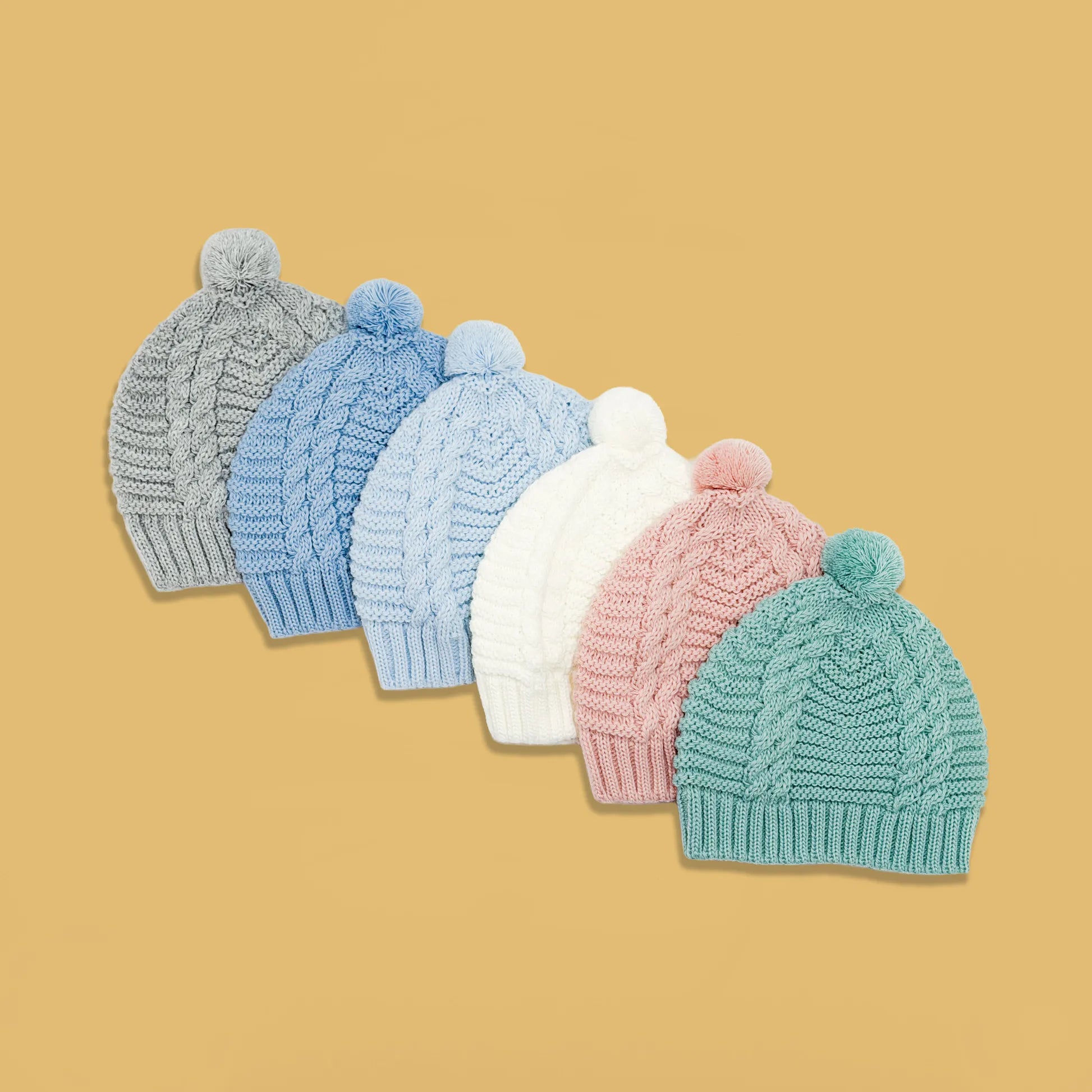 Gorros de punto trenzado con pompón en los colores gris, cobalto, azul, perla, rosa y verde