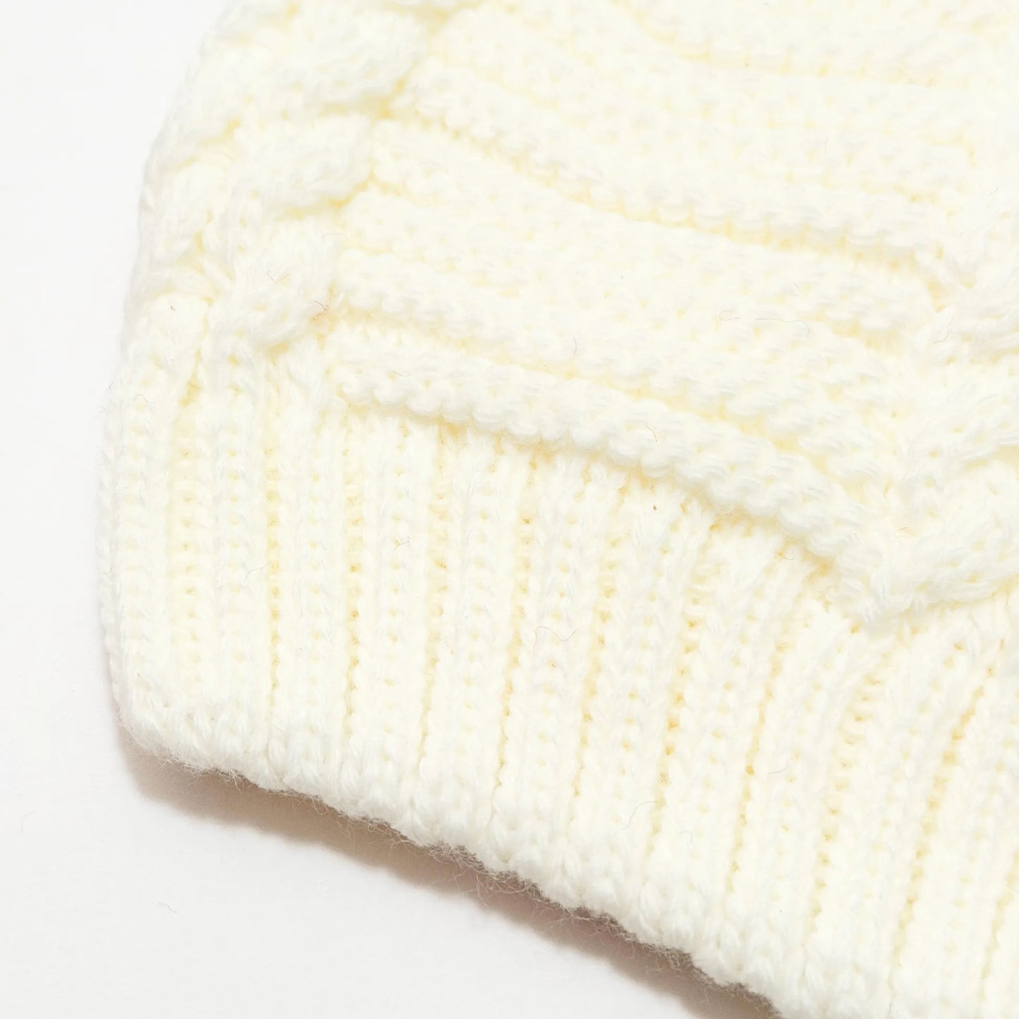 Detalle de gorro de punto trenzado con pompón perla