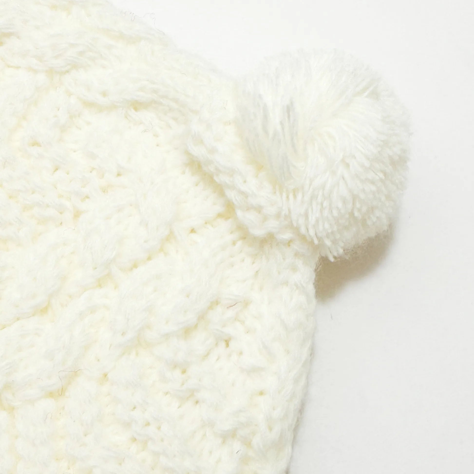 Detalle de gorro de punto trenzado con pompón perla