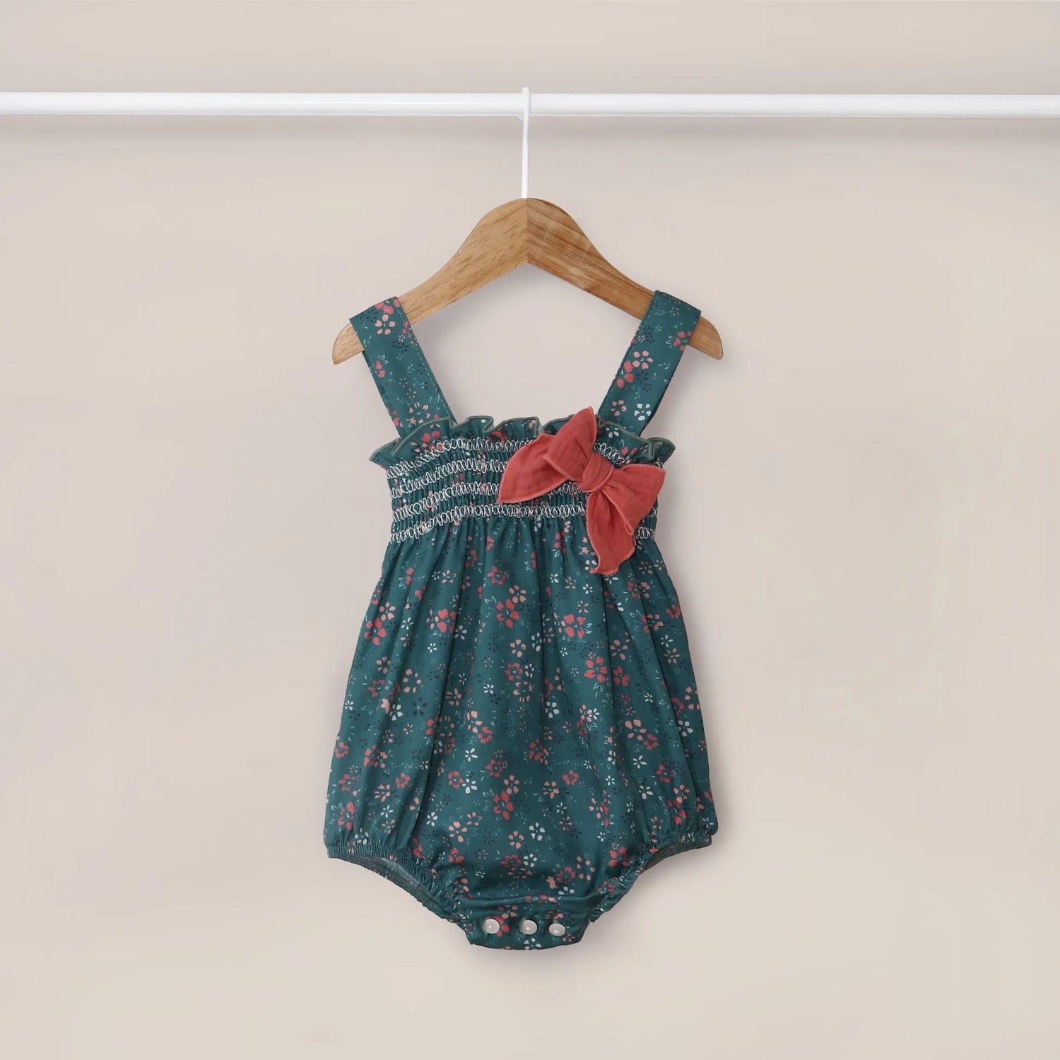 Peto de niña verde con estampado floral y lazo en el pecho coral en contraste