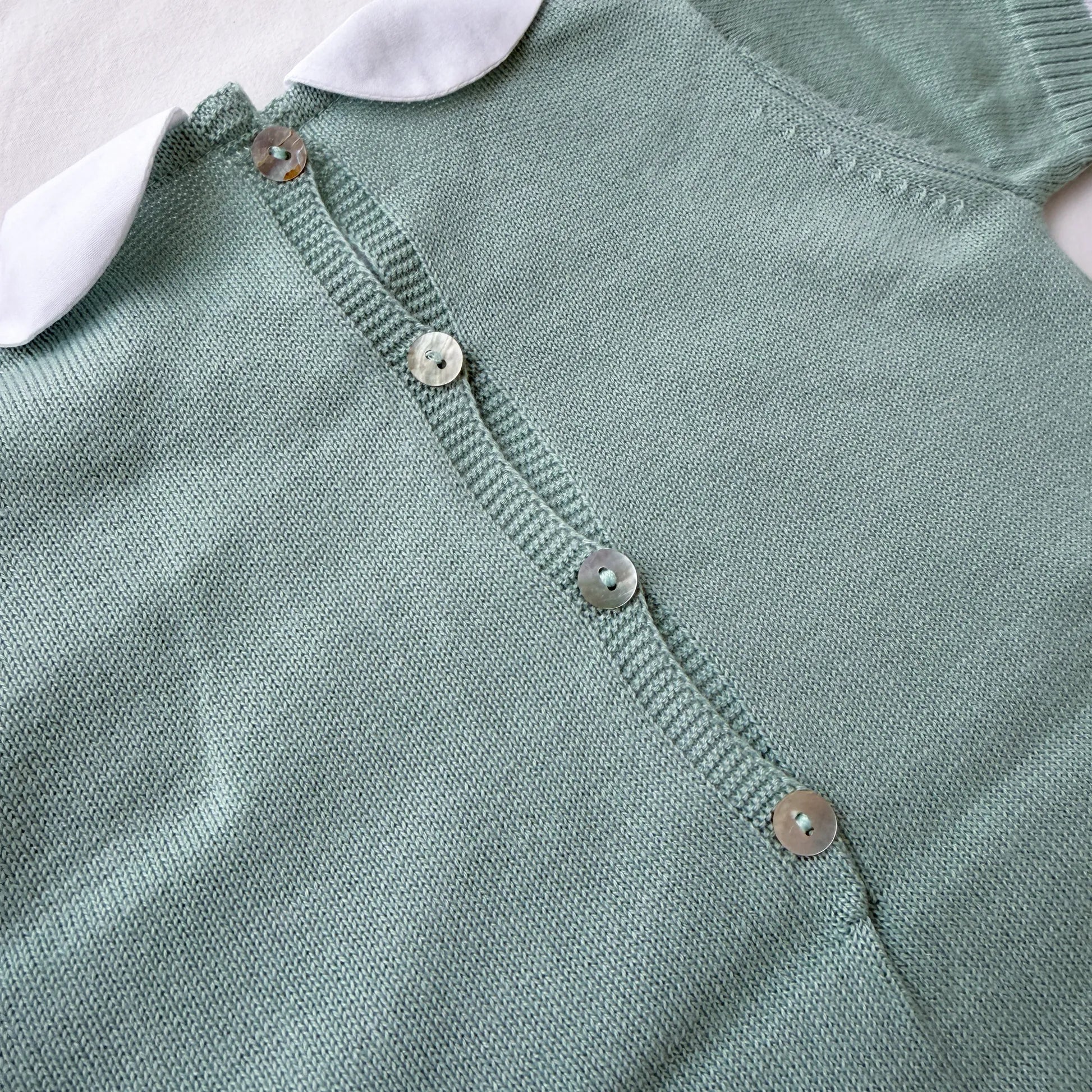 Detalle de mono de punto con cuello Peter Pan y motivo de osito verde