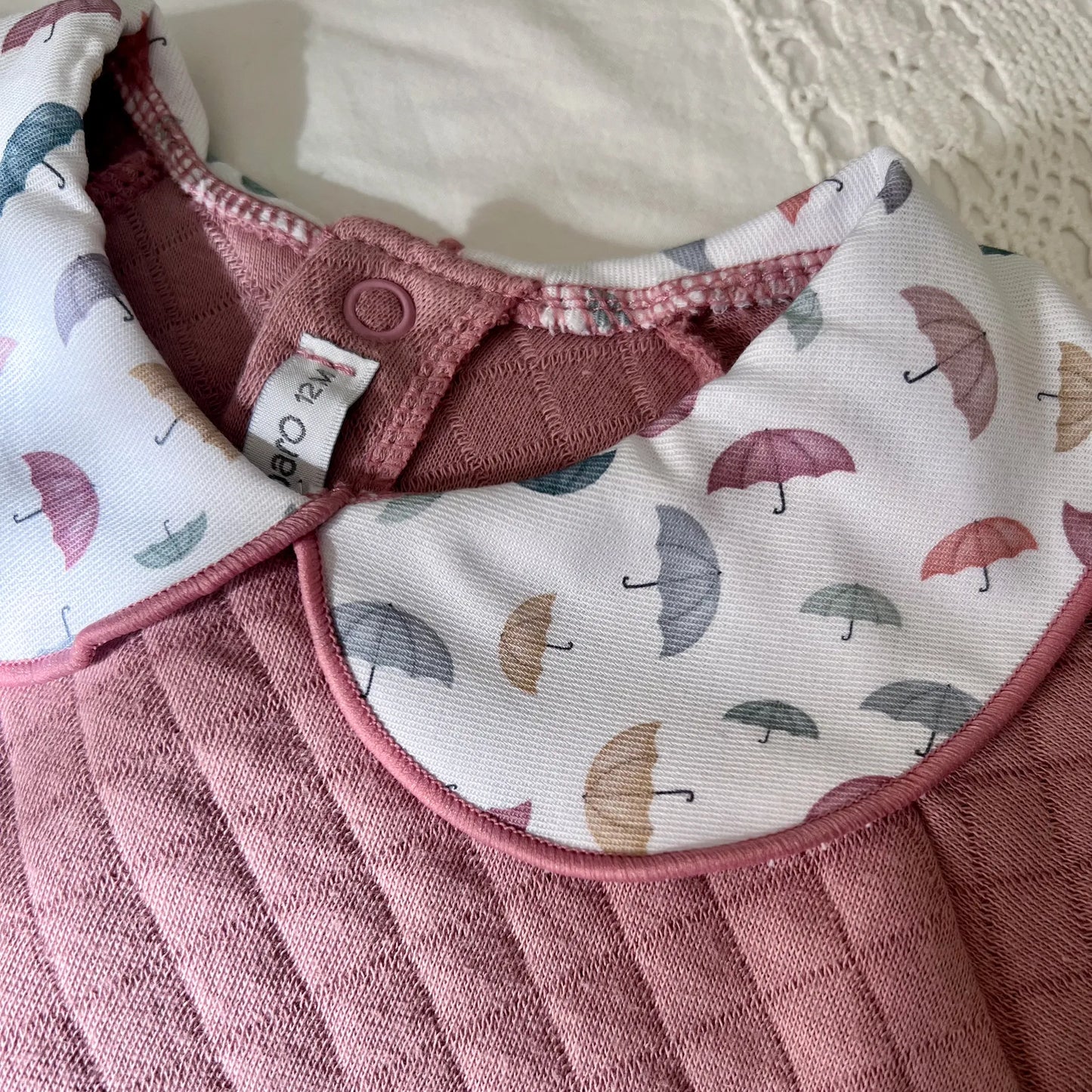 Detalle de pelele de niña con cuello redondo en contraste rosa
