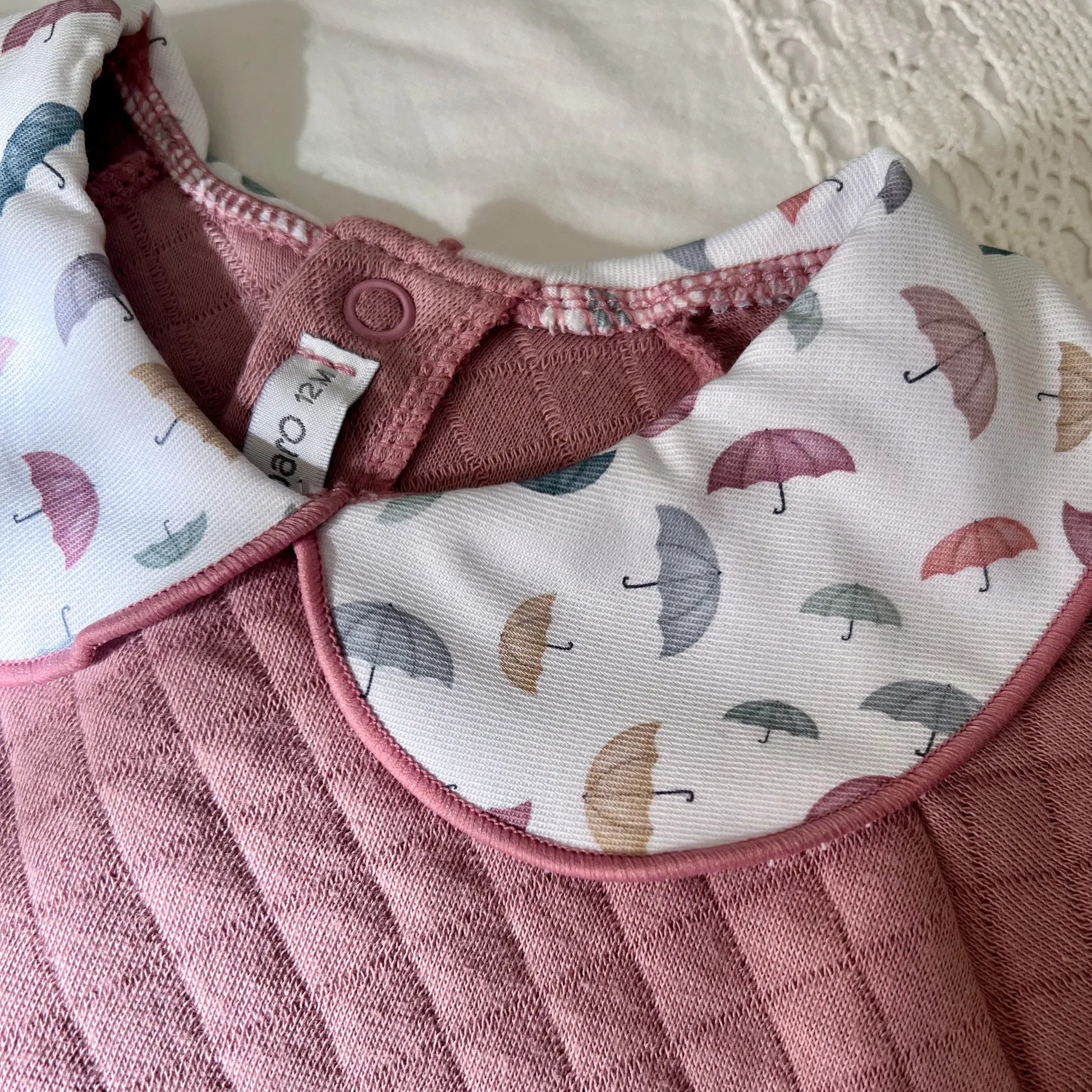 Detalle de pelele de niña con cuello redondo en contraste rosa