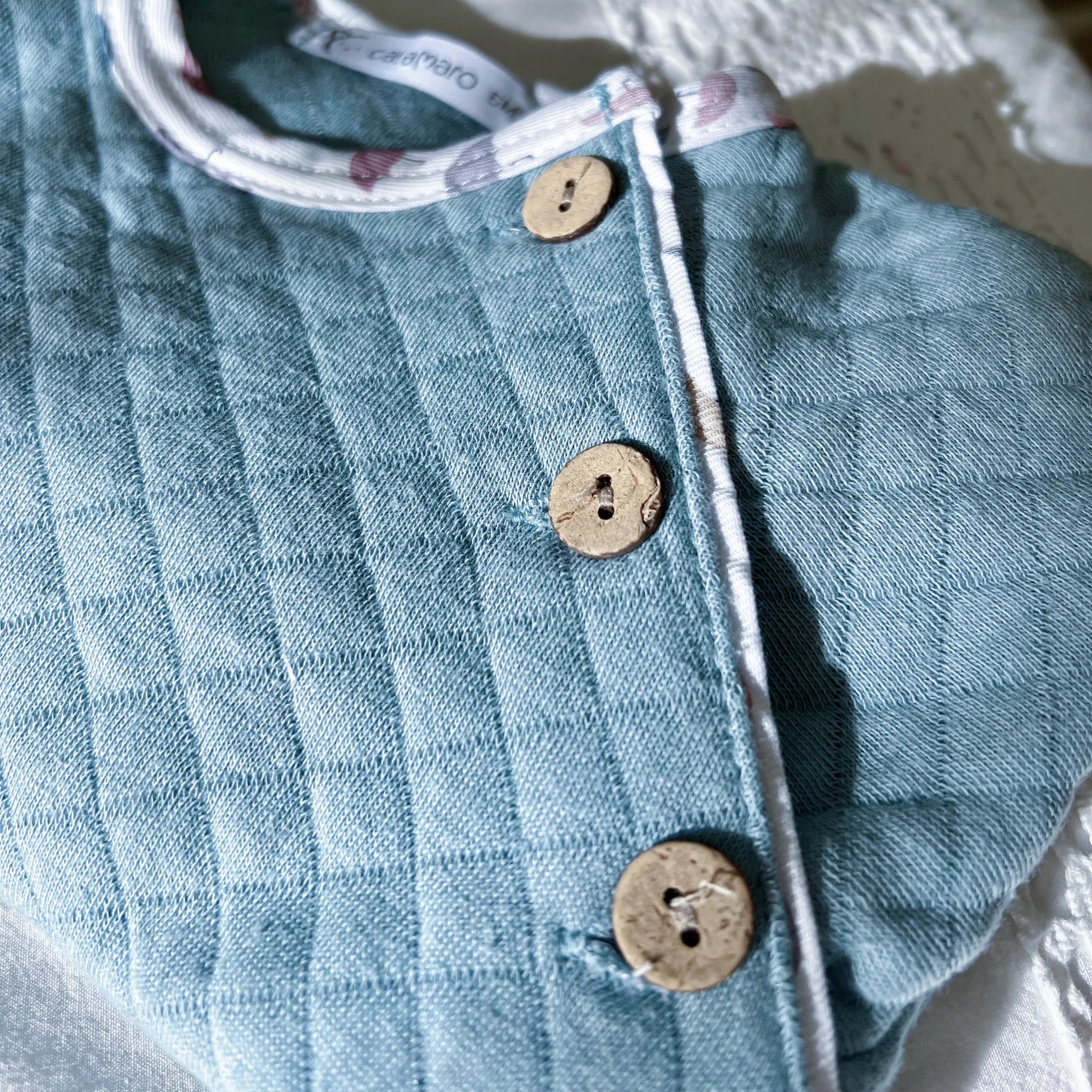 Detalle de pelele de niño con botones decorativos azul