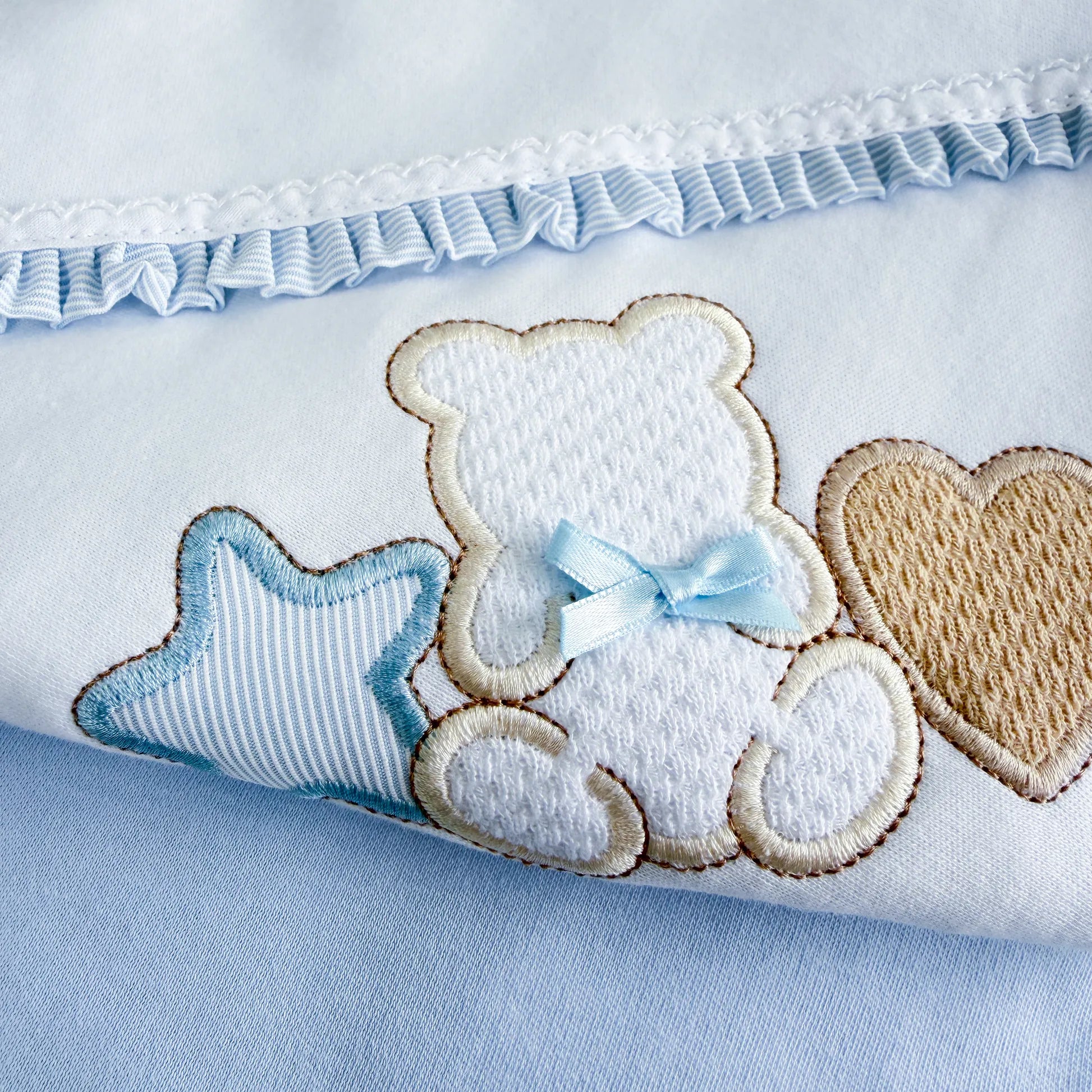 Detalle de manta de algodón con motivo de osito entre estrella y corazón azul