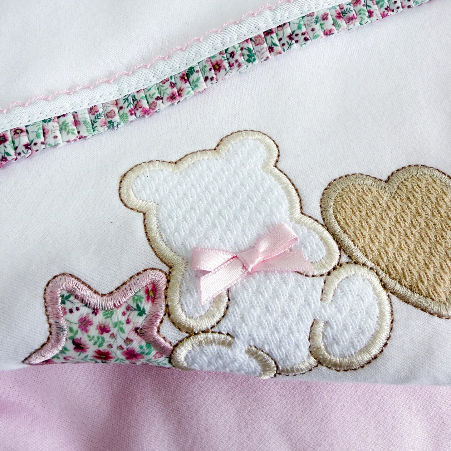 Detalle de manta de algodón con motivo de osito entre estrella y corazón rosa