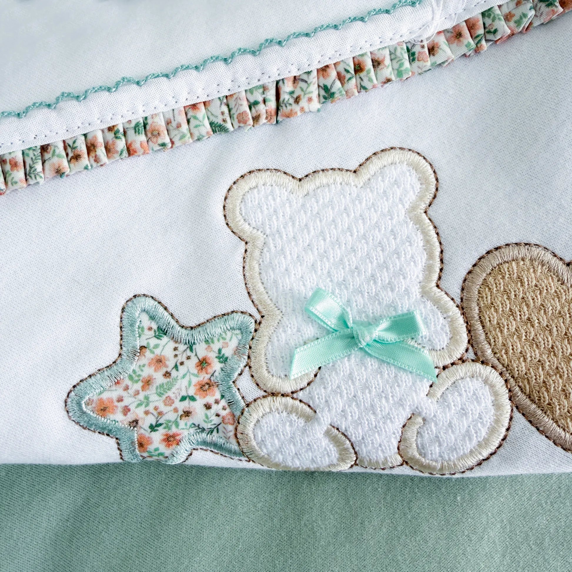 Detalle de manta de algodón con motivo de osito entre estrella y corazón verde