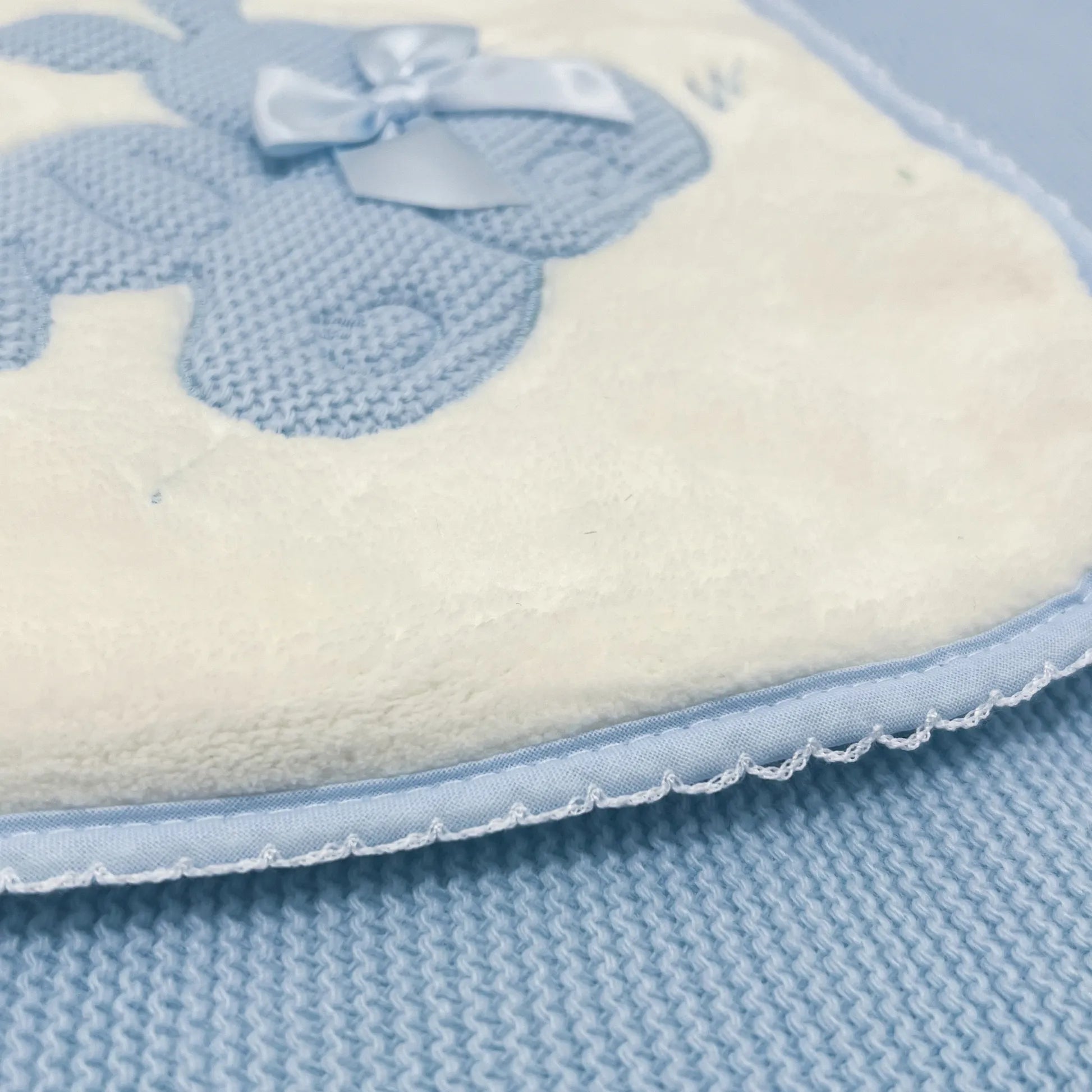Detalle de manta con motivo de conejos de punto y lazo azul
