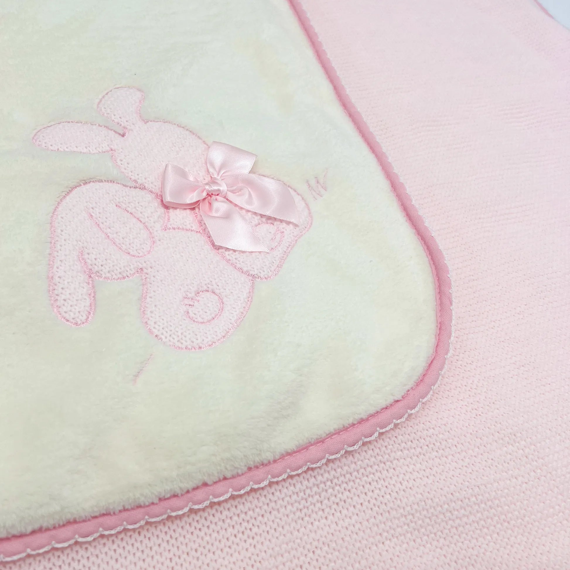 Detalle de manta con motivo de conejos de punto y lazo rosa