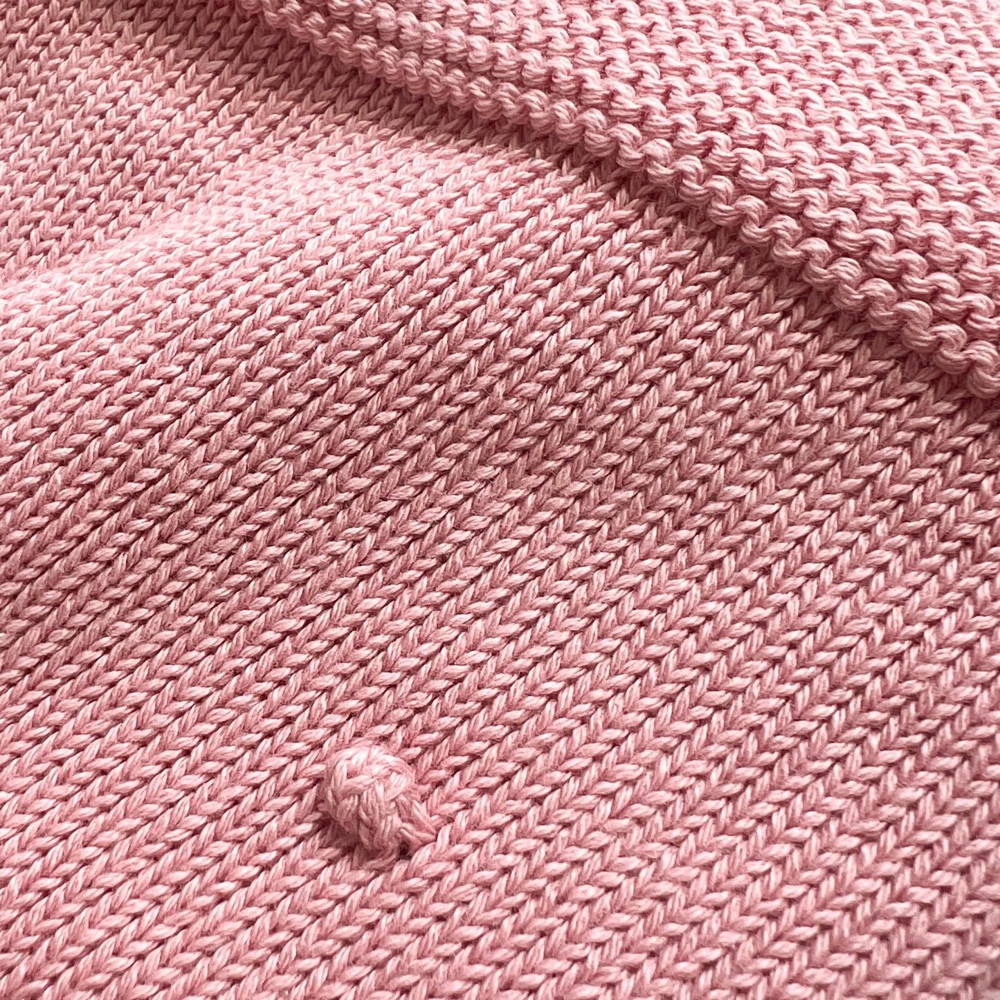 Detalle de manta de punto con relieve de pompones rosa