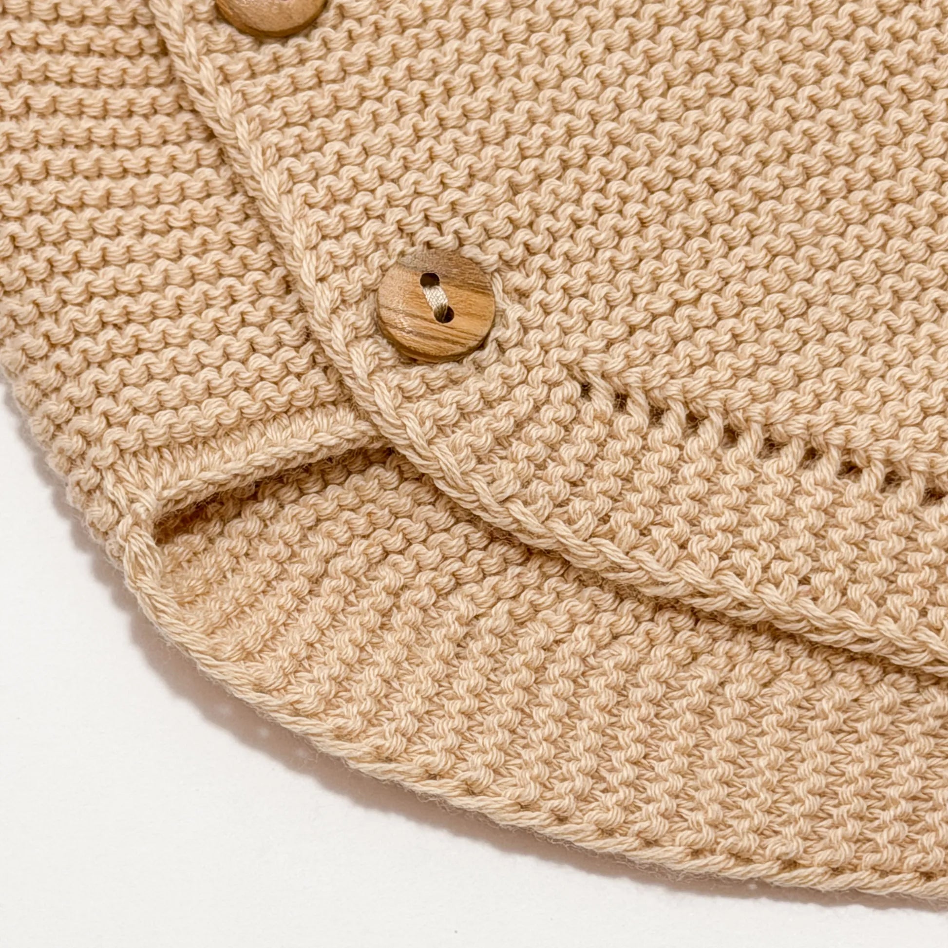 Detalle de cubrepañal de punto con botones de madera beige
