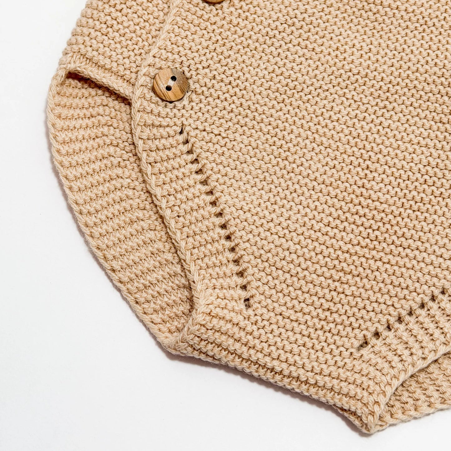 Detalle de cubrepañal de punto con botones de madera beige