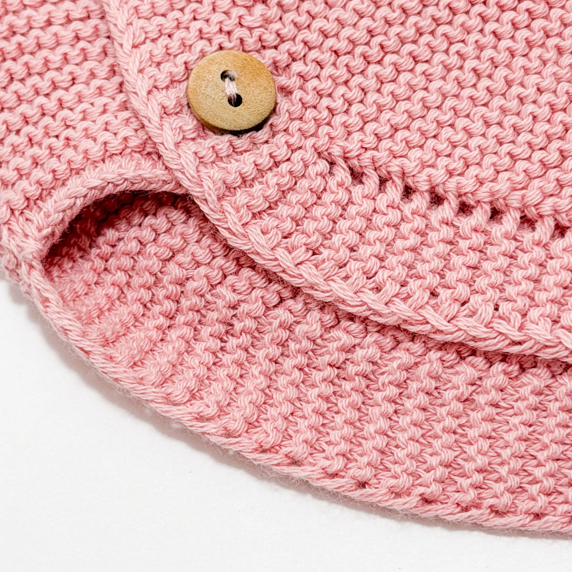 Detalle de cubrepañal de punto con botones de madera rosa