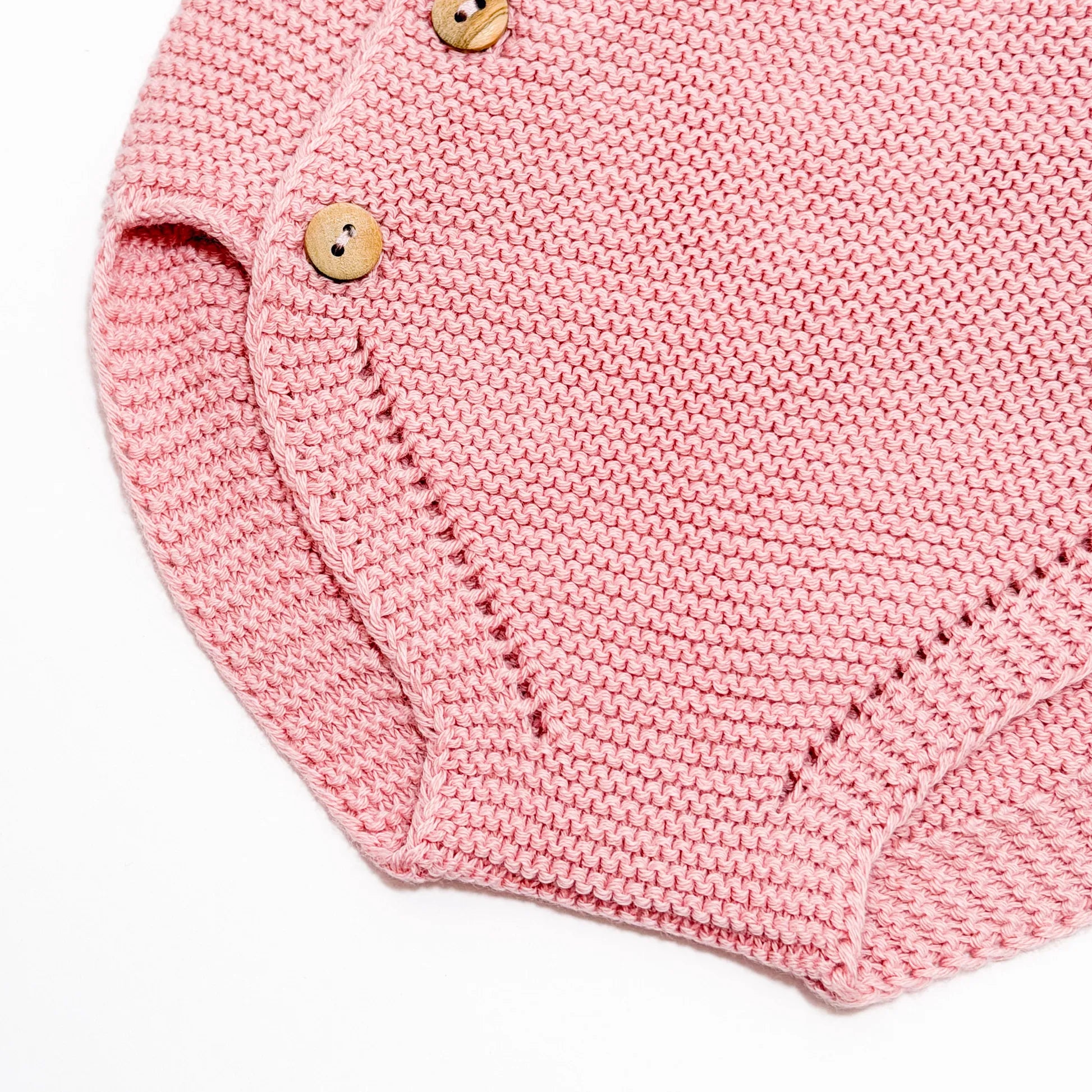 Detalle de cubrepañal de punto con botones de madera rosa