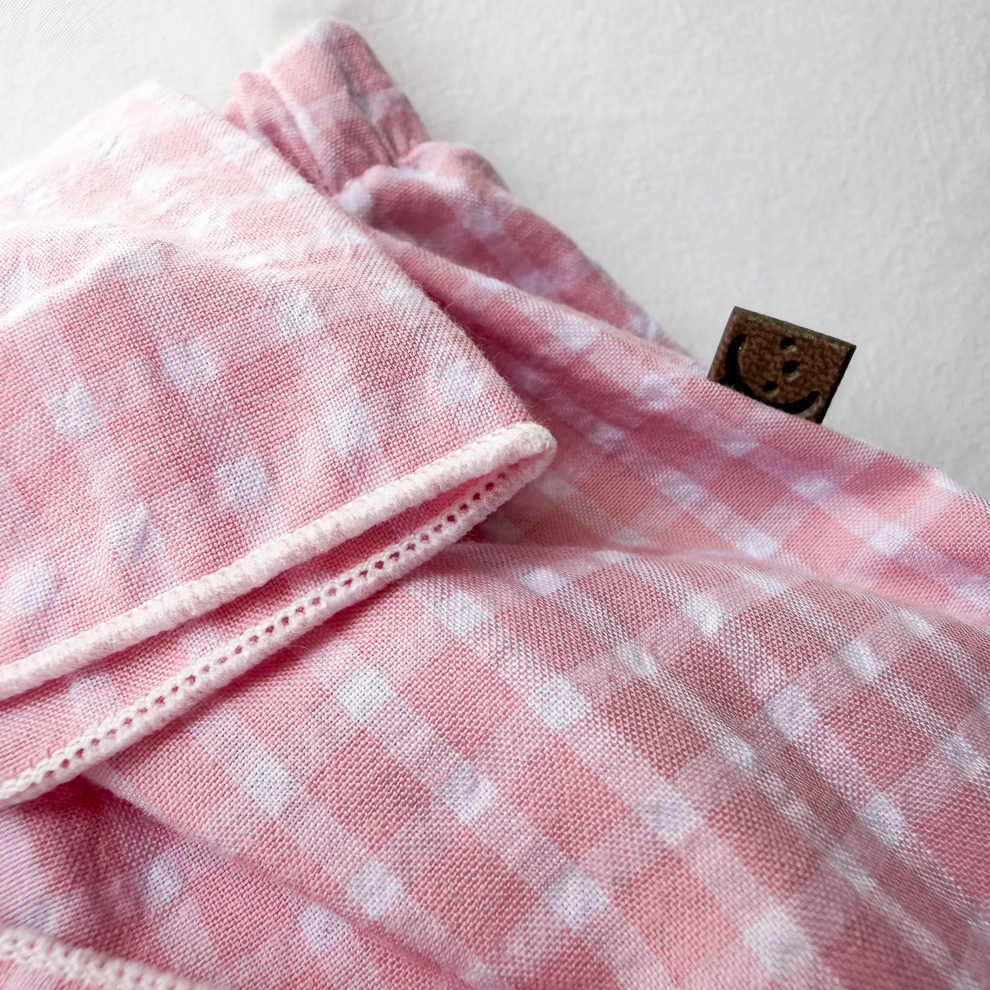 Detalle de cubrepañal de niña en tela con lazo delantero y volantes rosa
