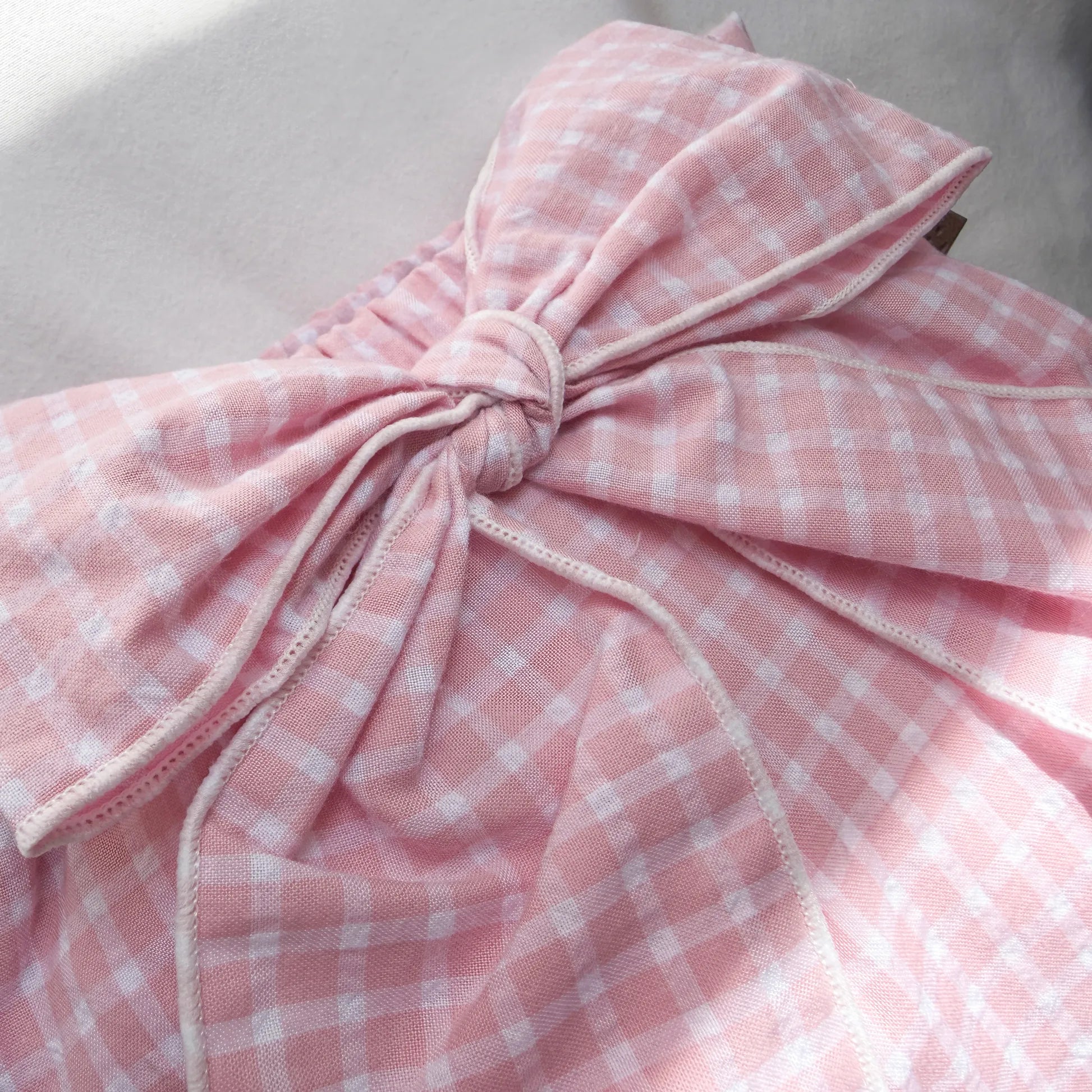 Detalle de cubrepañal de niña en tela con lazo delantero y volantes rosa
