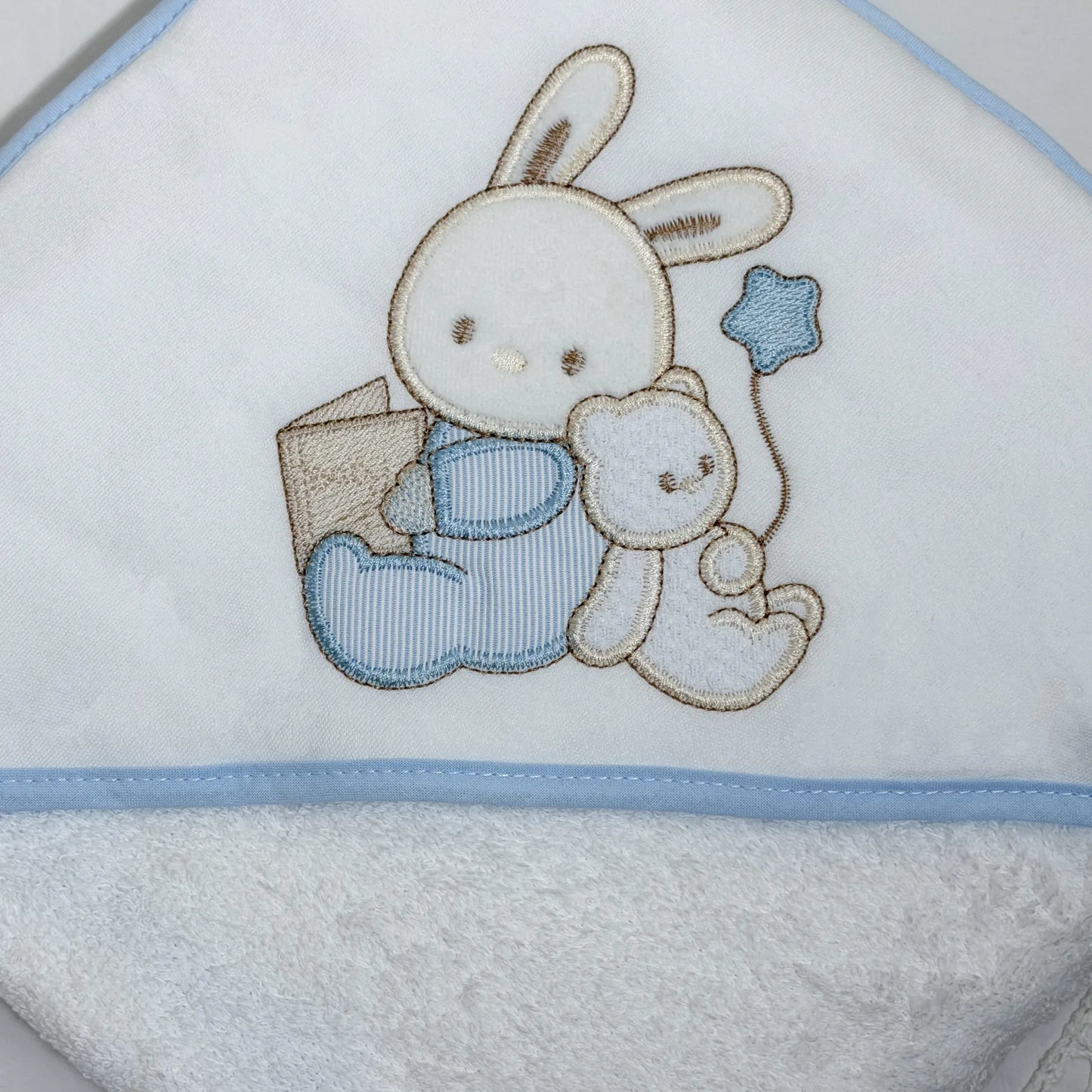 Detalle de toalla con motivo de conejito y osito con libro azul