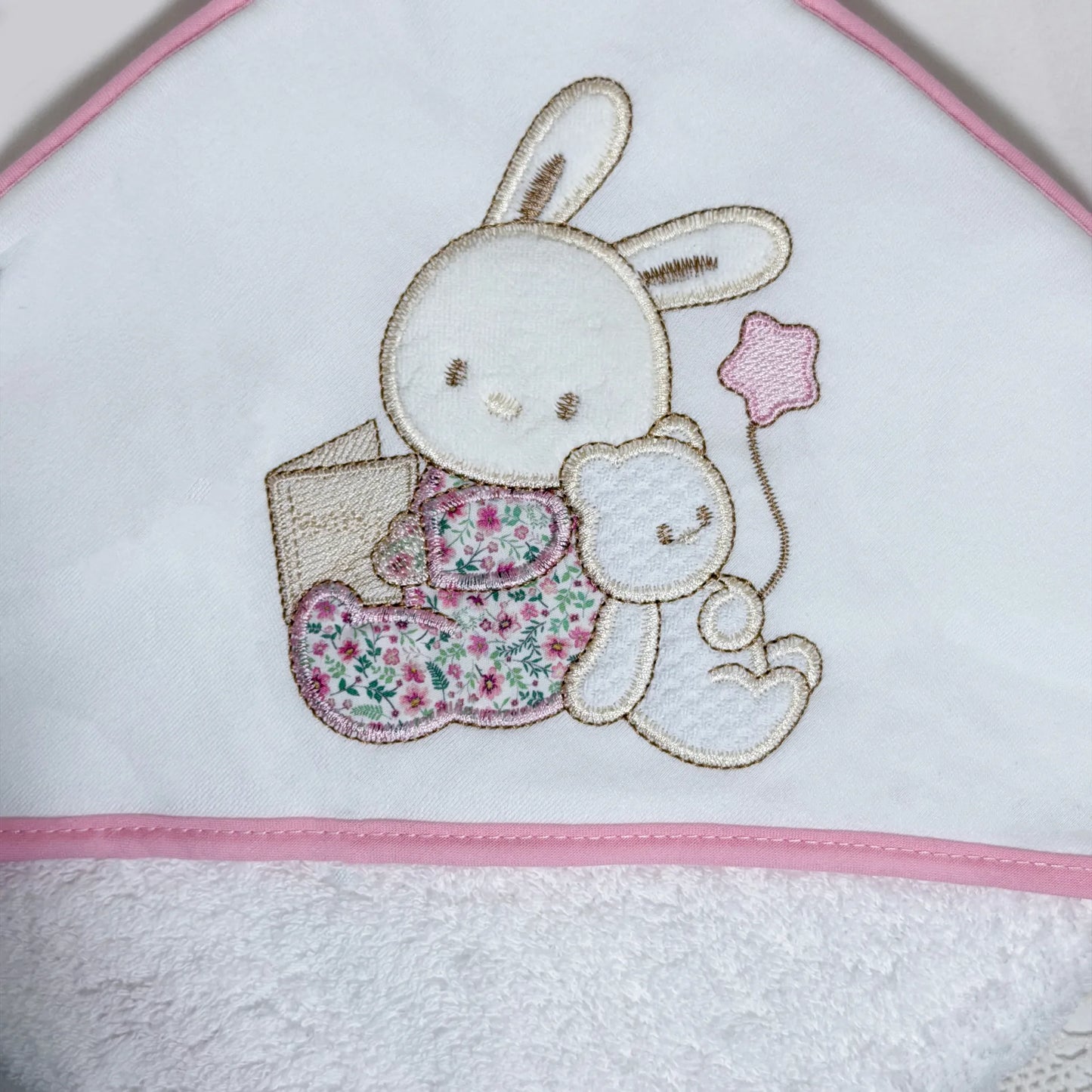 Detalle de toalla con motivo de conejito y osito con libro rosa