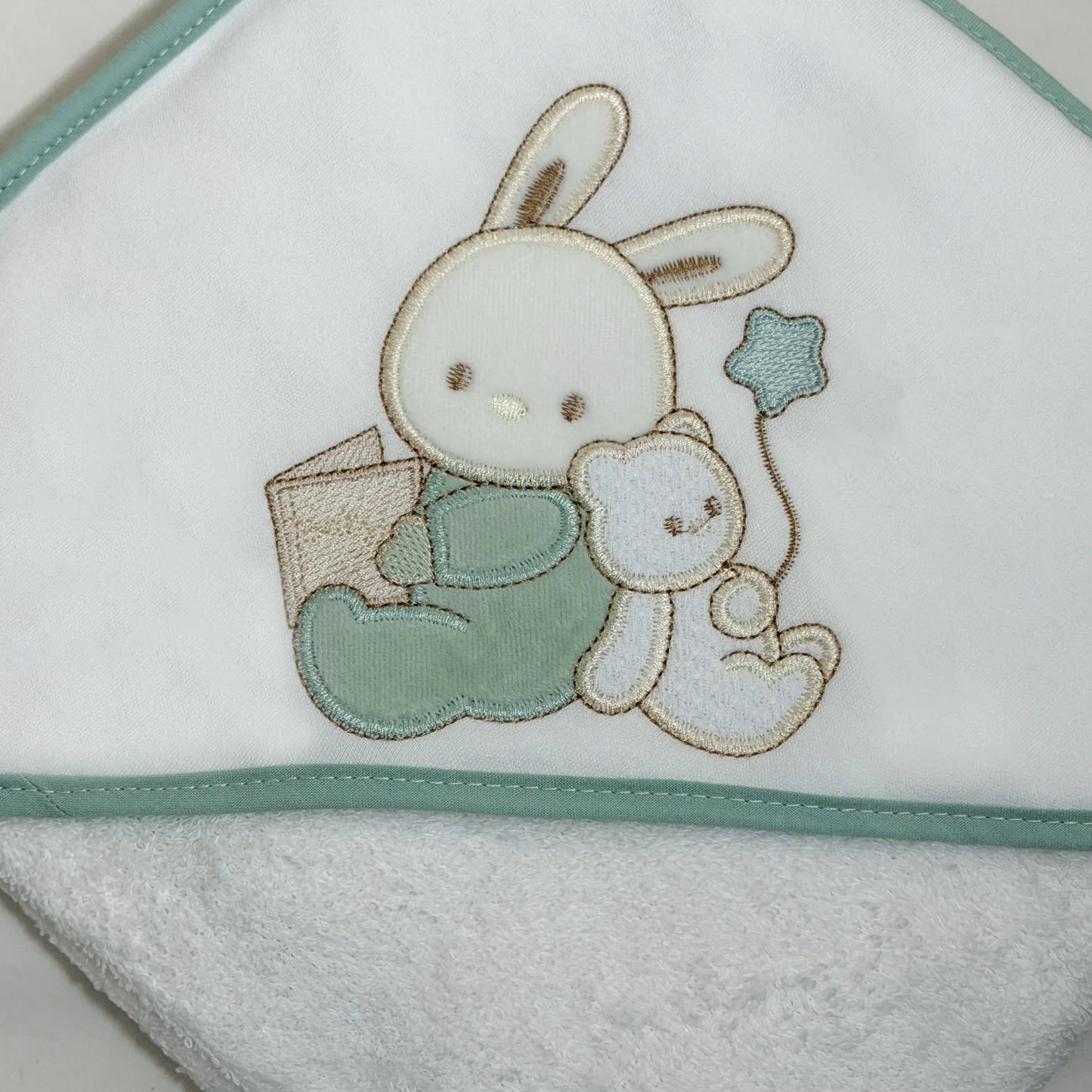 Detalle de toalla con motivo de conejito y osito con libro verde