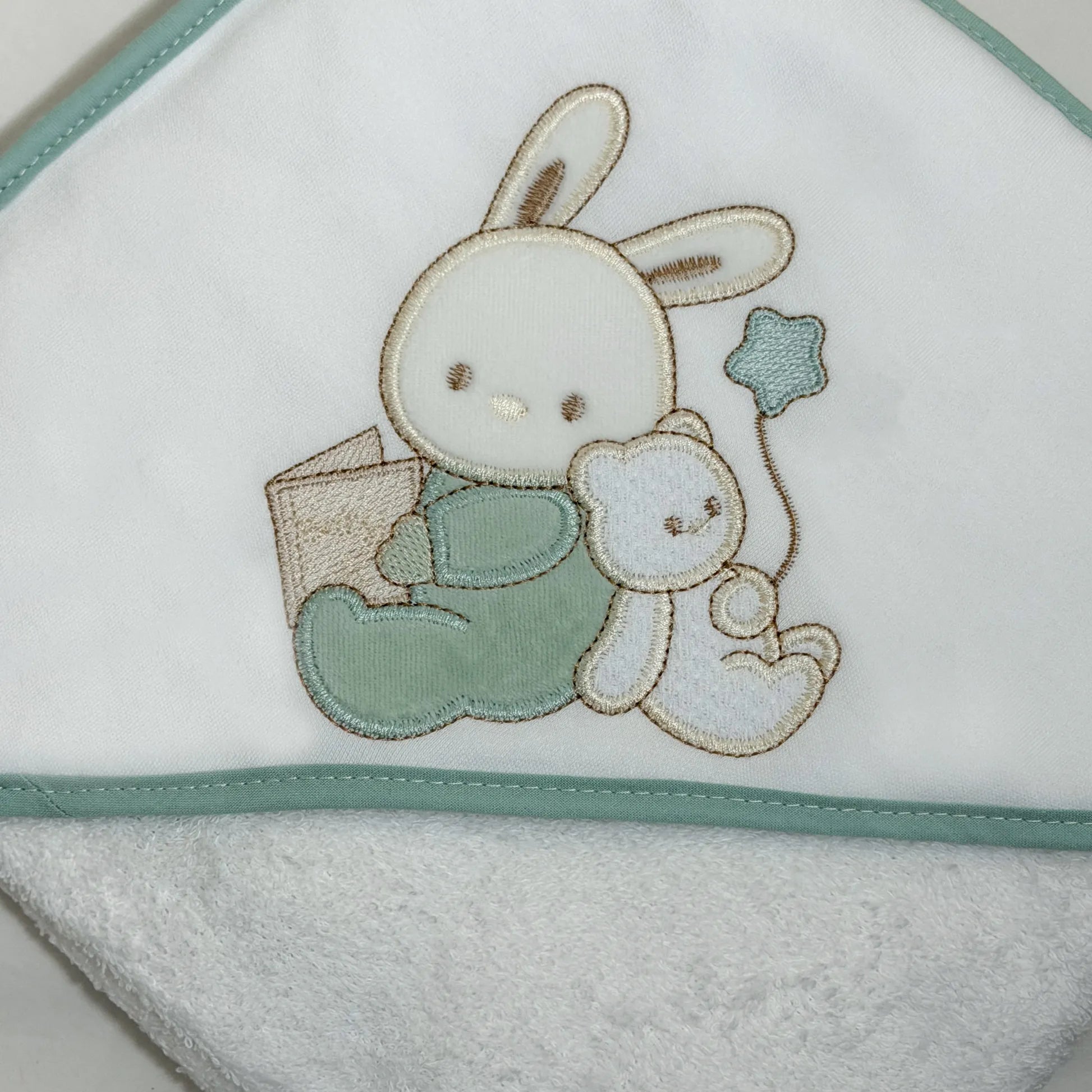 Detalle de toalla con motivo de conejito y osito con libro verde