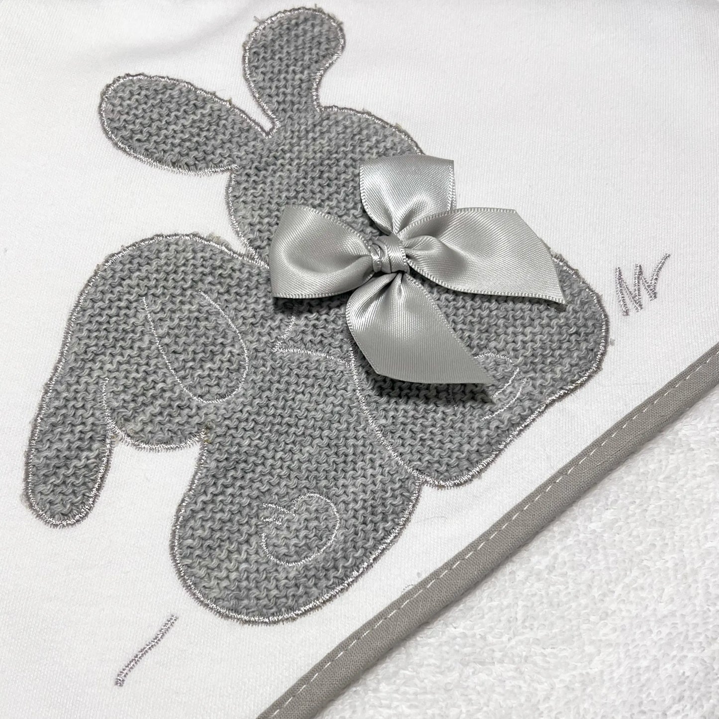 Detalle de toalla con motivo de conejos de punto y lazo gris