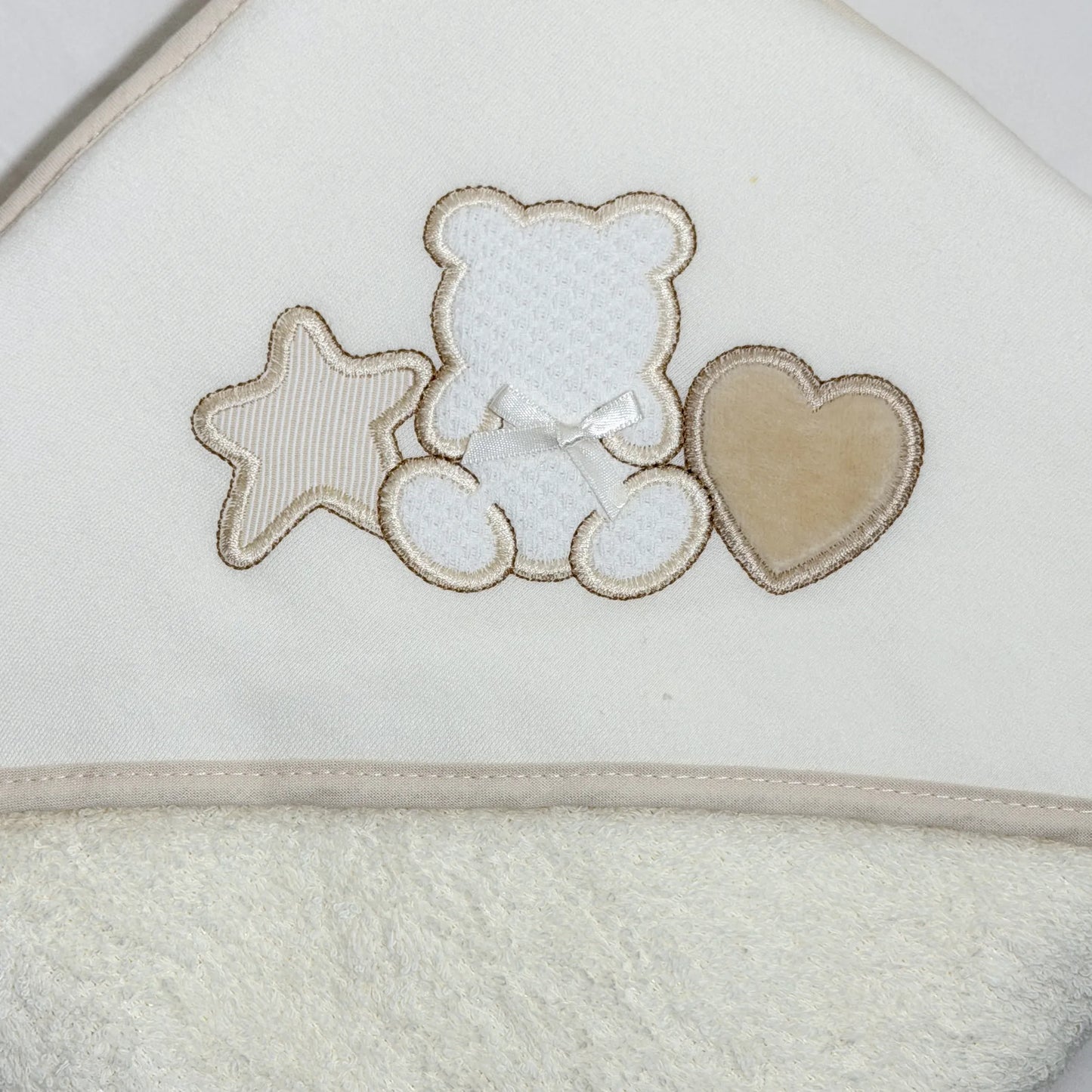 Detalle de toalla con motivo de osito entre estrella y corazón perla