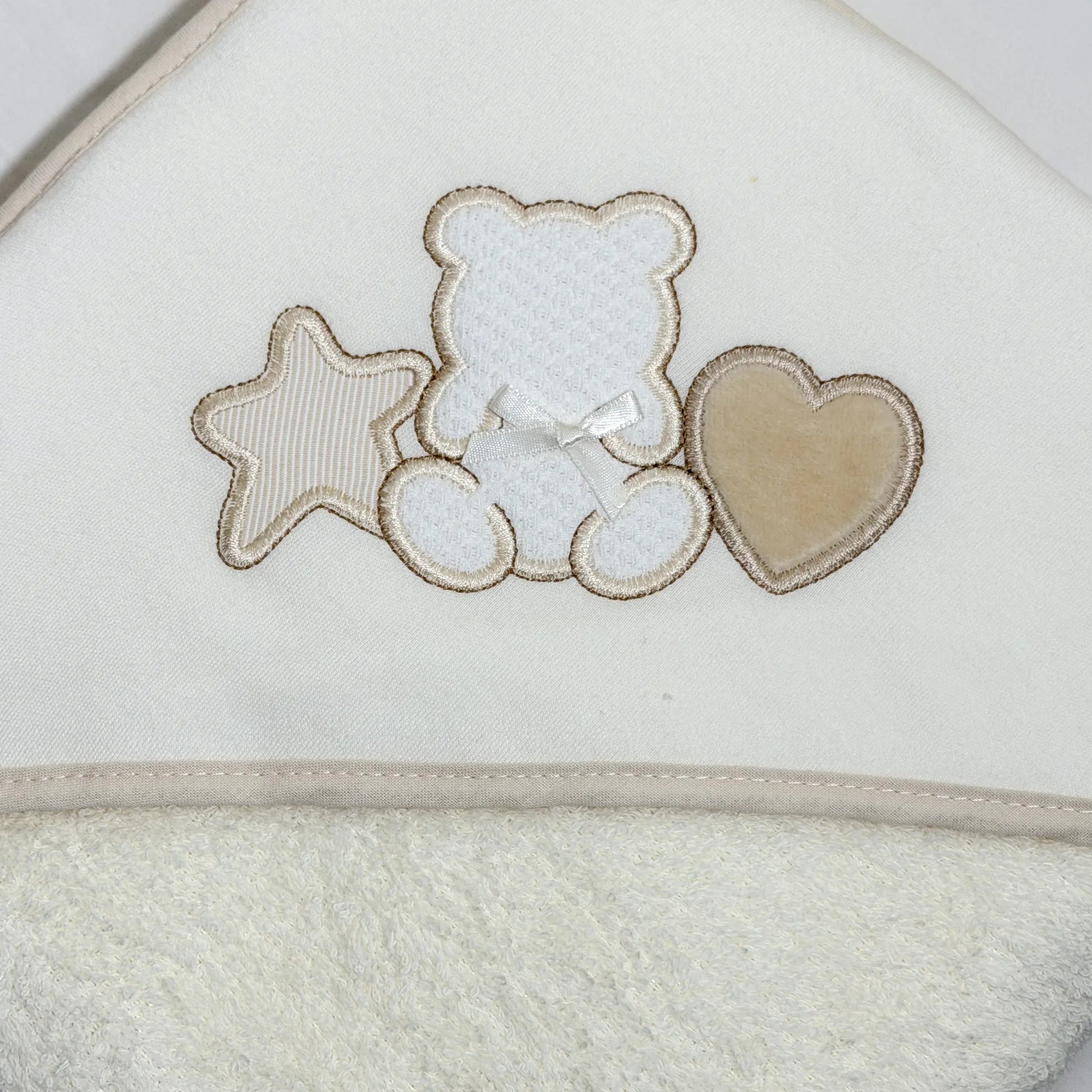 Detalle de toalla con motivo de osito entre estrella y corazón perla