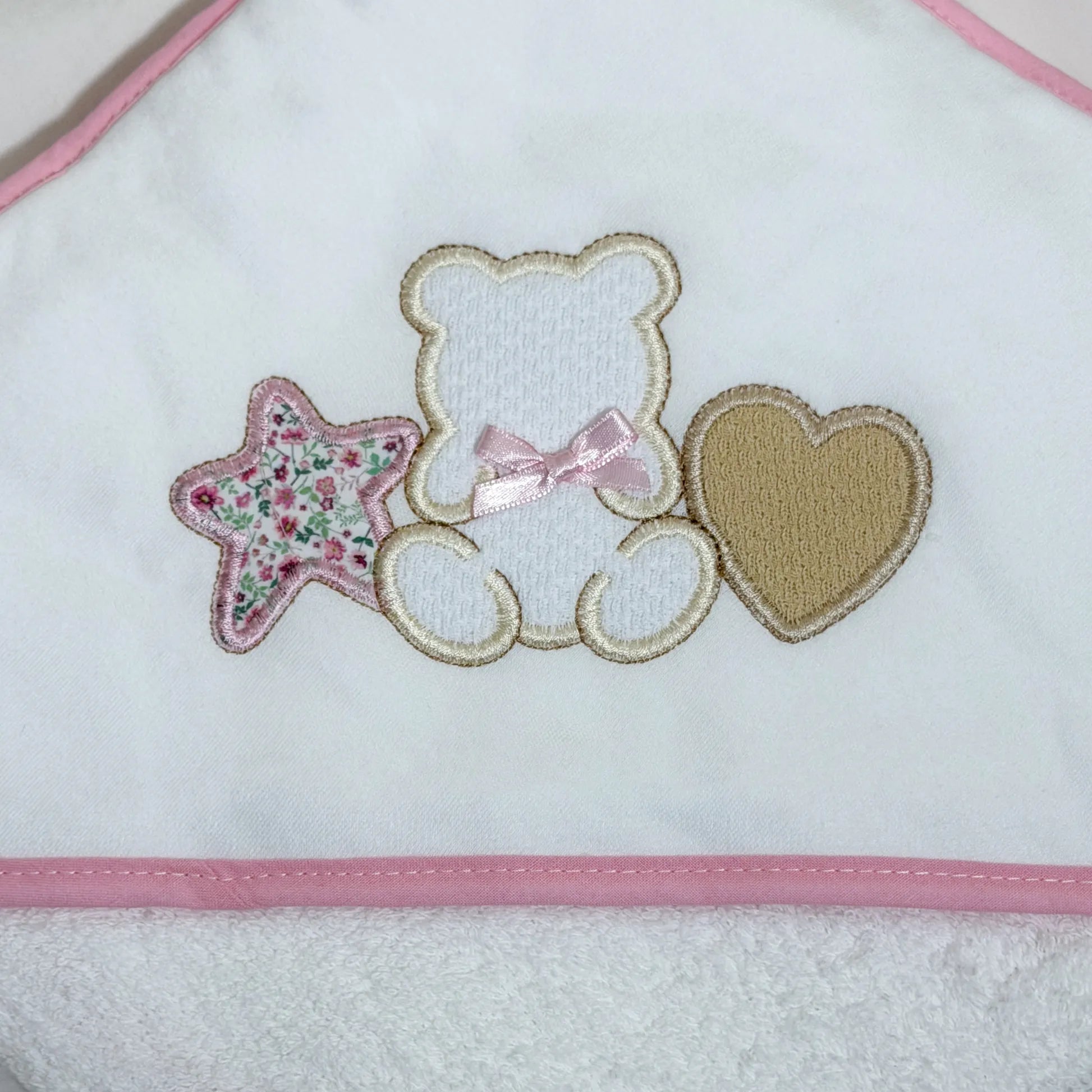 Detalle de toalla con motivo de osito entre estrella y corazón rosa