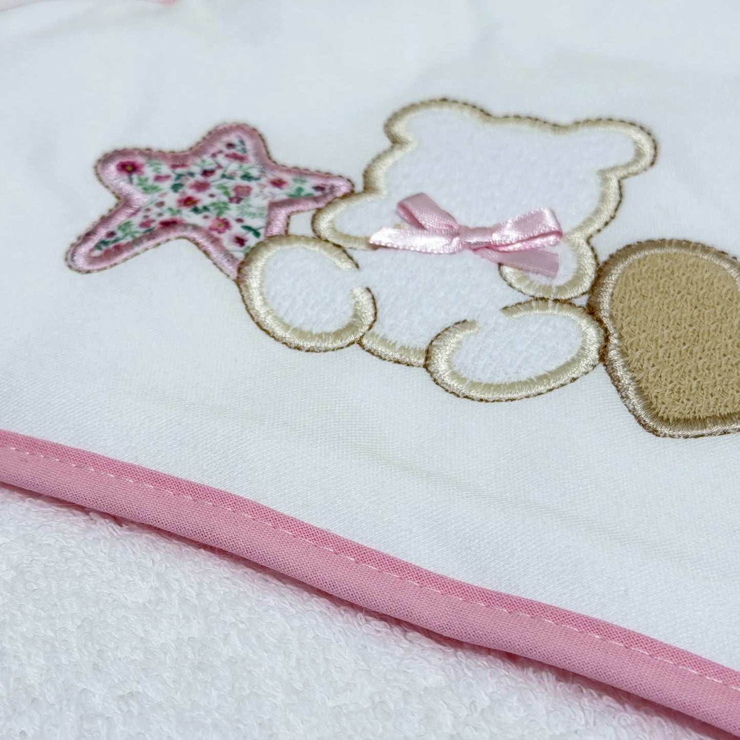 Detalle de toalla con motivo de osito entre estrella y corazón rosa