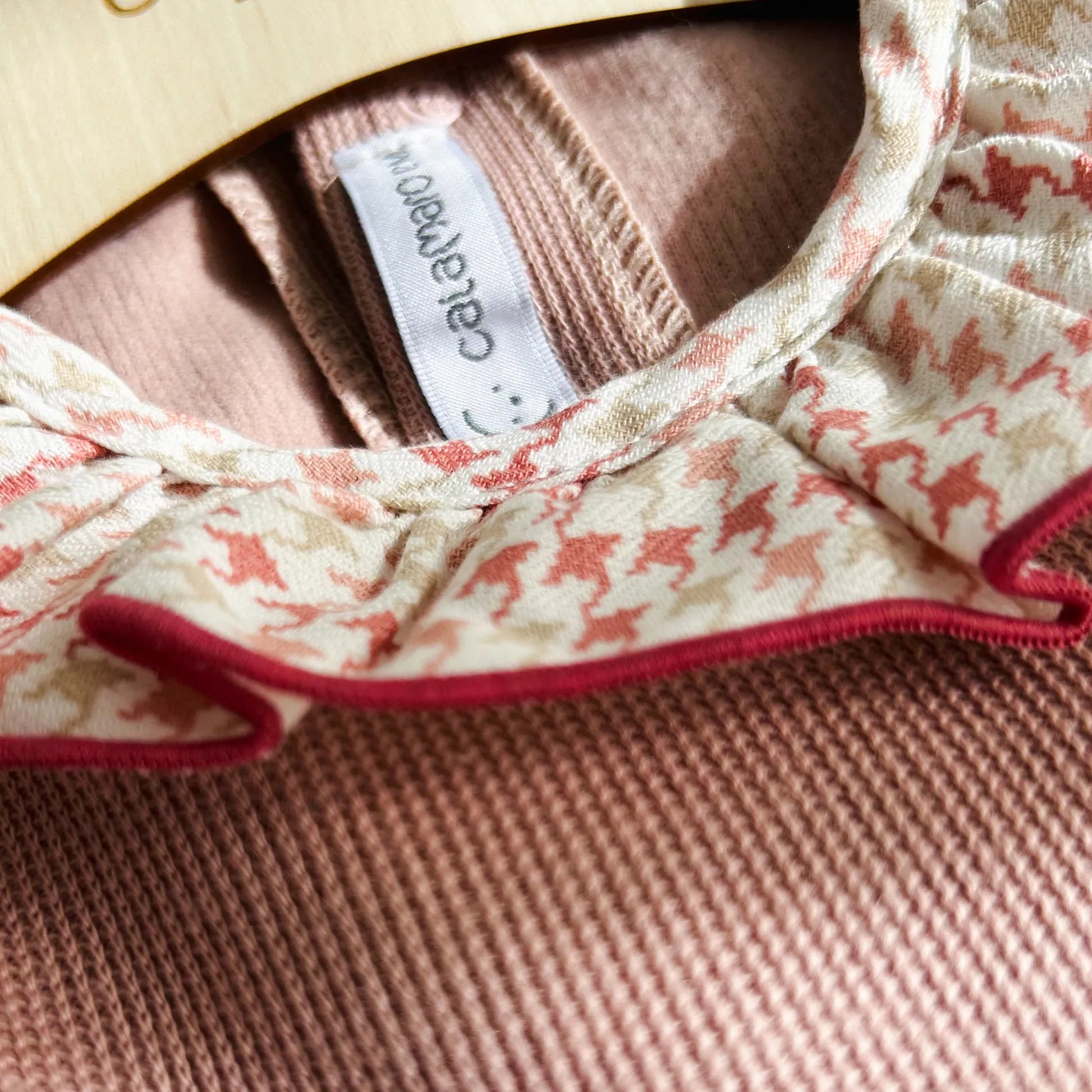 Detalle de vestido con volante en el cuello y puños y lazo en la cintura rosa
